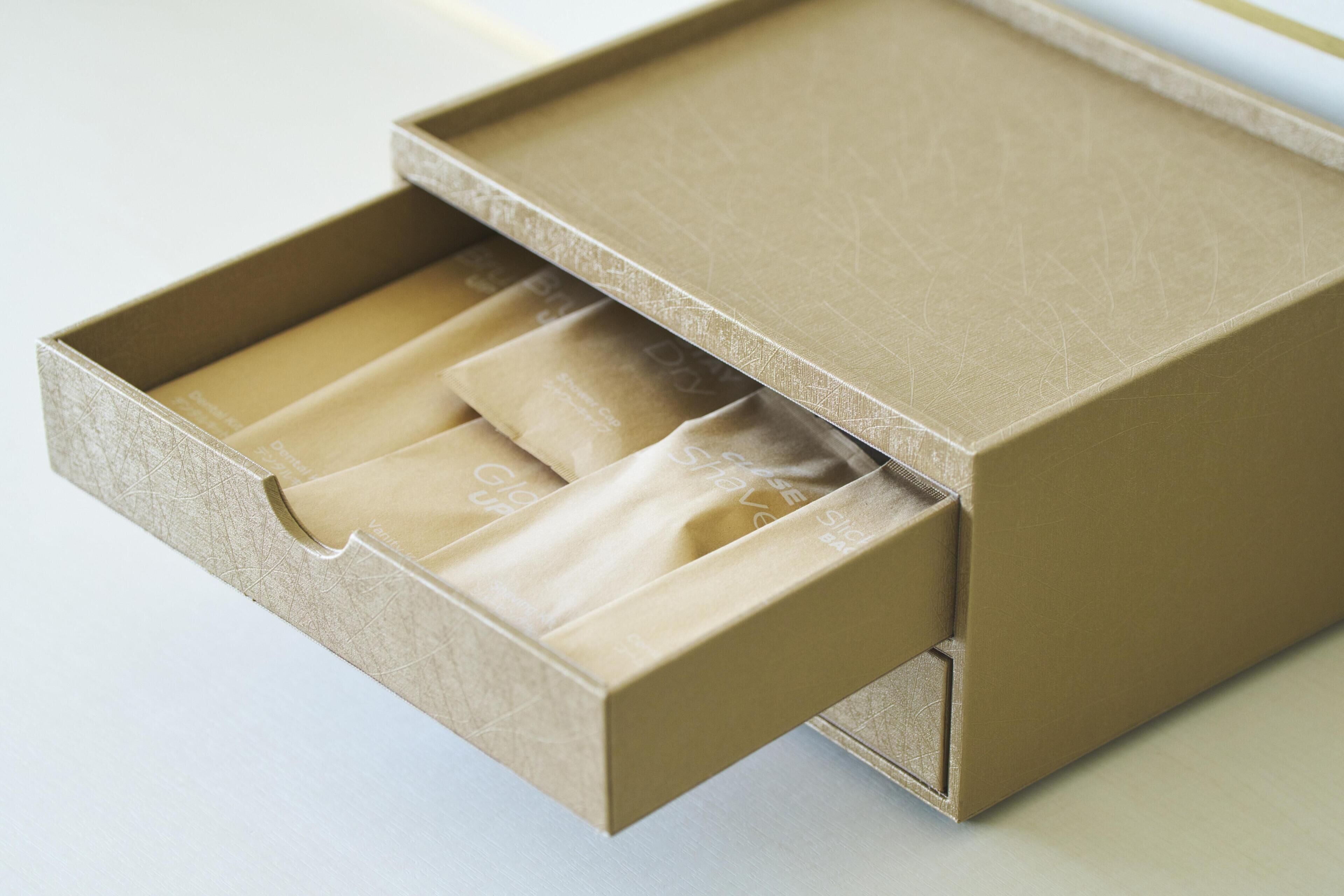 Een kartonnen doos met een lade met daarin meerdere beige enveloppen.