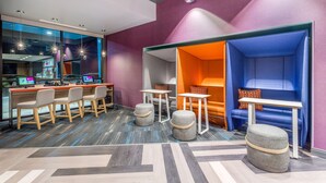 A modern hotel lobby with a bar area, seating, and a reception desk. - Tru by Hilton Madison West, WI (Madison)