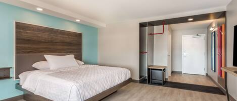 Un dormitorio moderno con una cama, una mesita de noche y una puerta que da a un pasillo.