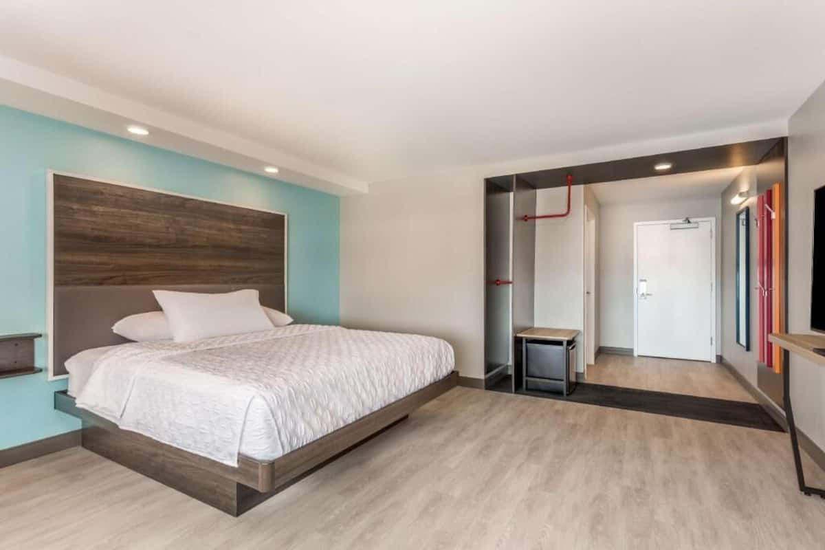 Une chambre moderne avec un lit, un petit bureau et une porte donnant sur une autre pièce.