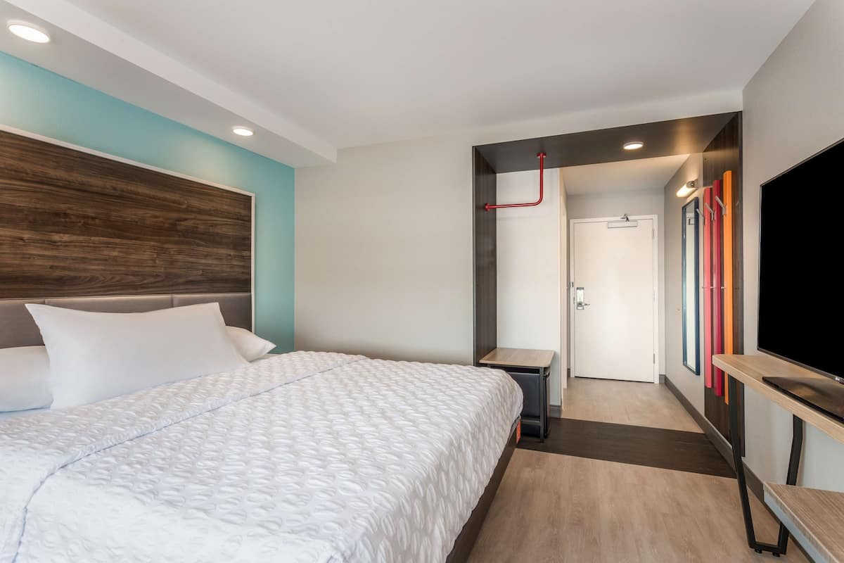 Une chambre d’hôtel moderne avec un grand lit, une télévision et une petite table.