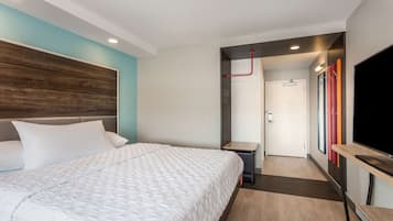 Una habitación de hotel moderna con una cama grande, un televisor y una mesita.