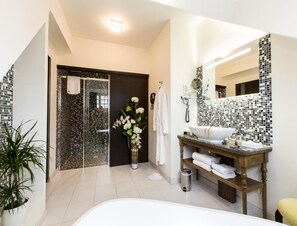 Un baño moderno con un espejo grande, un lavamanos blanco y una zona de ducha.