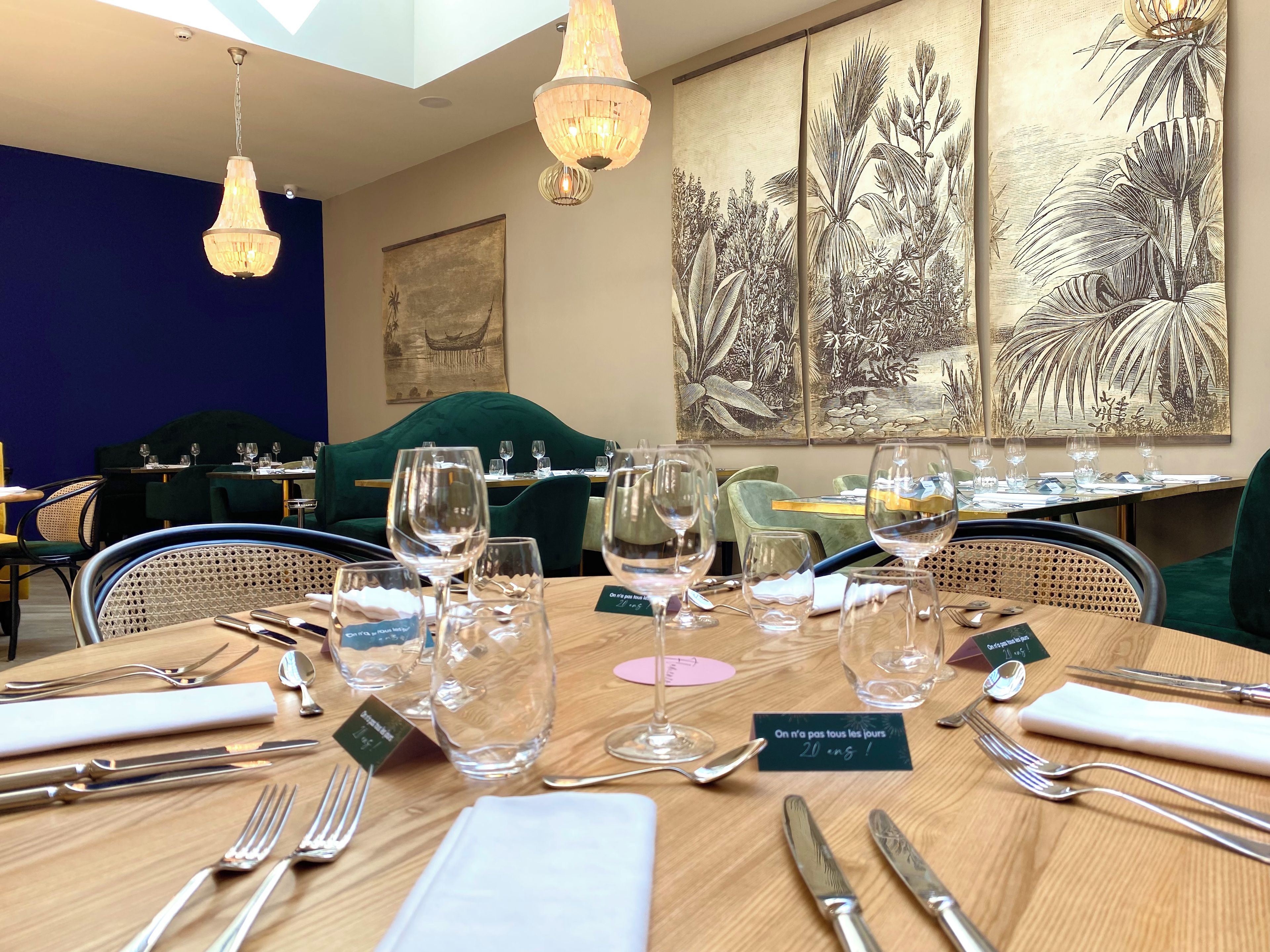 Ein Restaurantambiente mit gedeckten Tischen, klarem Glas und Besteck, sowie Kunstwerken an den Wänden.