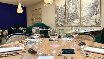 Ein Restaurantambiente mit gedeckten Tischen, klarem Glas und Besteck, sowie Kunstwerken an den Wänden.