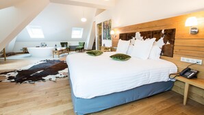 A spacious bedroom with a large bed, wooden headboard, and a wooden floor. There is a small bedside table with a lamp and a phone. - Hotel Marotte (Amiens)