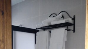 A bathroom with a toilet, a towel rack with multiple towels, and a shower area. - Posada Y Bungalows La Capilla (Ezequiel Montes)