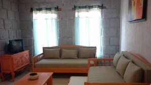 A cozy living room with a sofa, a wooden coffee table, and a television on a cabinet. - Posada Y Bungalows La Capilla (Ezequiel Montes)