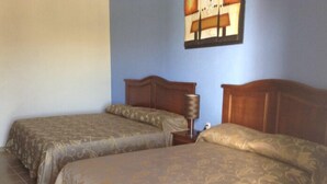 A hotel room with two beds, a nightstand, and a wall-mounted lamp. - Posada Y Bungalows La Capilla (Ezequiel Montes)