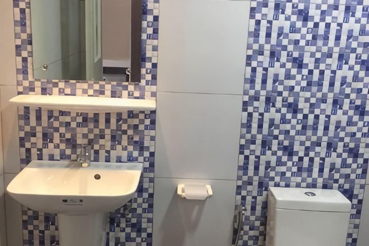 Casa de banho com lavatório, espelho e paredes revestidas a azulejos.