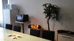 A dining area with a table, chairs, a microwave, a toaster, a small plant, and a cabinet. - Sultanias Melanchthon (Nuremberg)