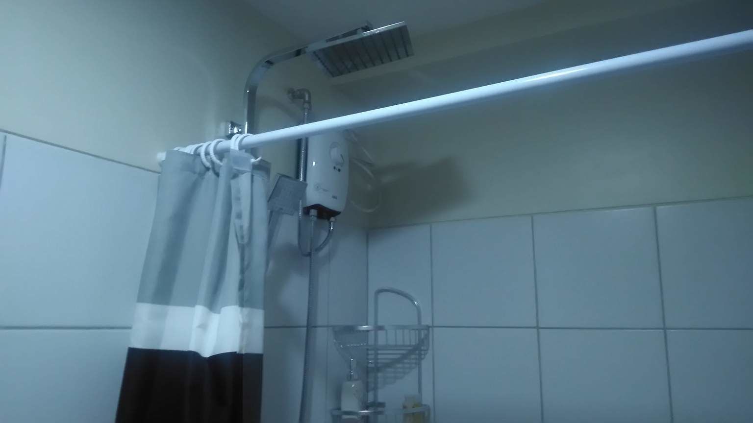 A bathroom with a shower, a towel rack, and a hand dryer.