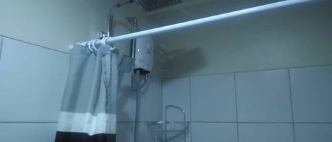 A bathroom with a shower, a towel rack, and a hand dryer.