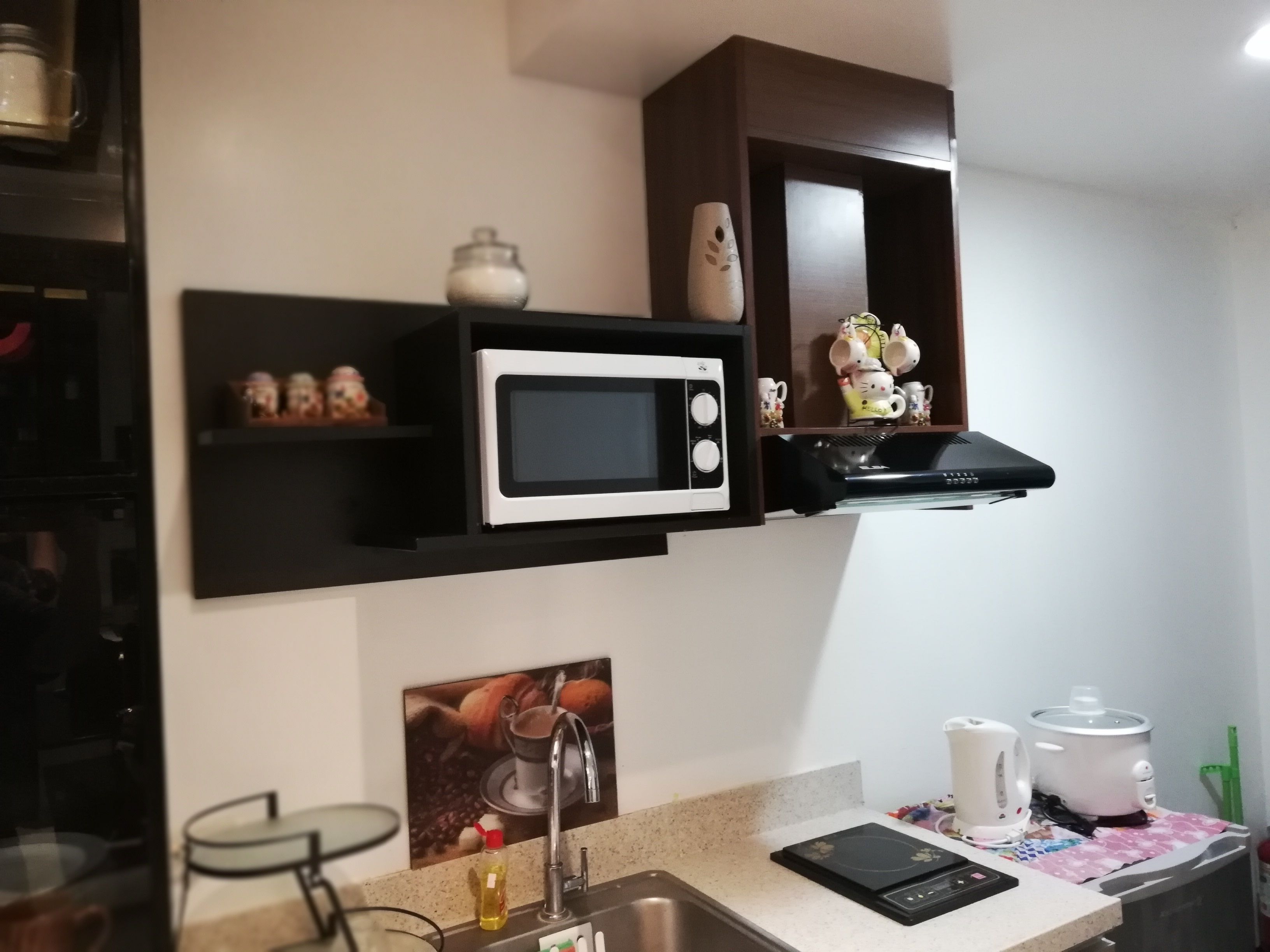 A kitchen with a microwave, a kettle, a slow cooker, and a coffee maker on the counter.