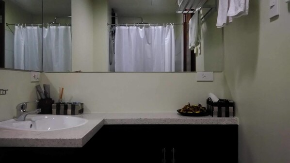 Un baño con lavamanos blanco, un espejo y una cortina de ducha.