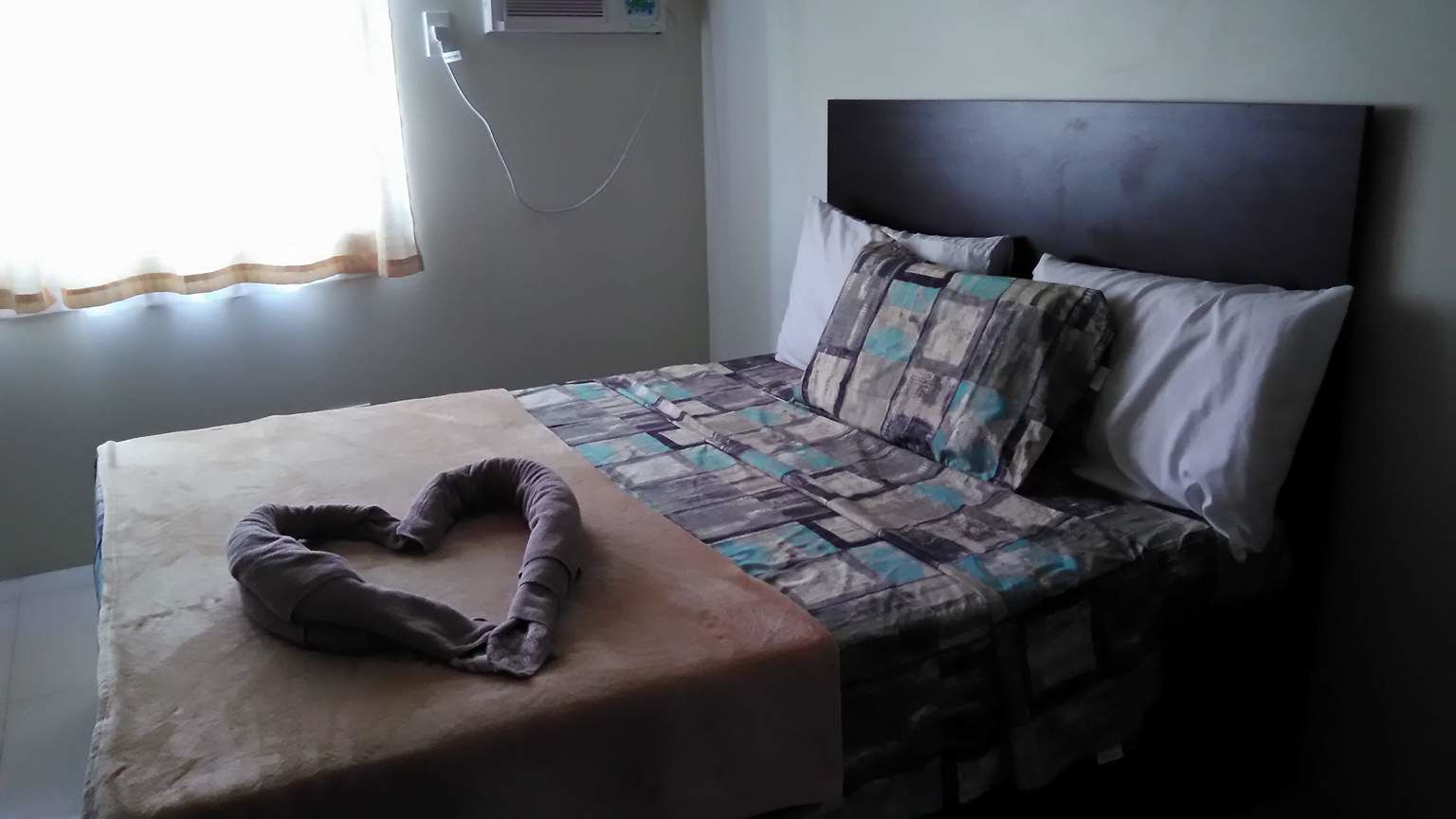 A bed with a quilt, pillows, and a headboard.