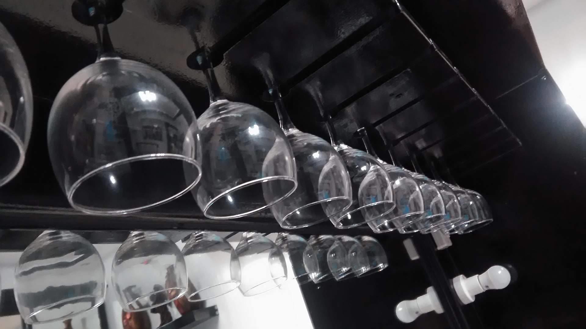 A row of empty wine glasses hanging from a ceiling.