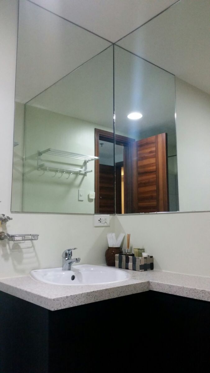 A bathroom with a large mirror, a sink, and a towel rack.