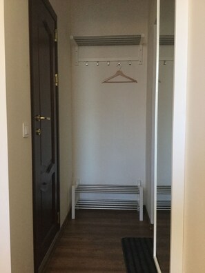 A hallway with a dark door, a white bench, and a coat rack. - easeApartments on Panagyurishte str. (Sofia)
