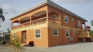 A two-story building with a balcony, multiple windows, and a staircase leading to the upper floor. - Ri'Biero's Holiday Apartments (Crown Point)