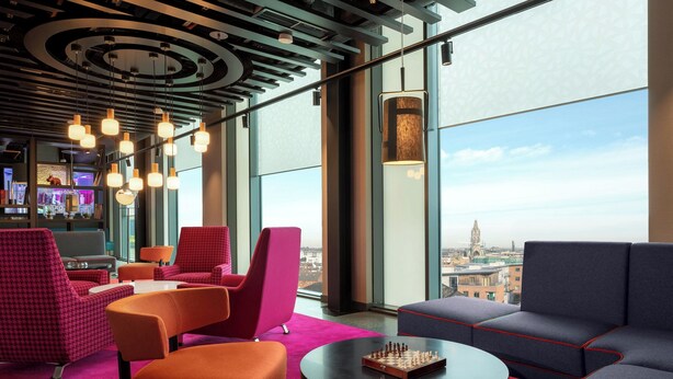 Un área de estar moderna con una amplia vista a través de un ventanal, un bar y un tablero de ajedrez sobre una mesa.