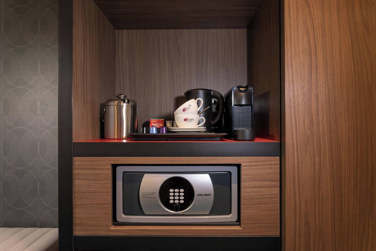 Una kitchenette con cafetera, hervidor de agua y dispensador de cápsulas de café.