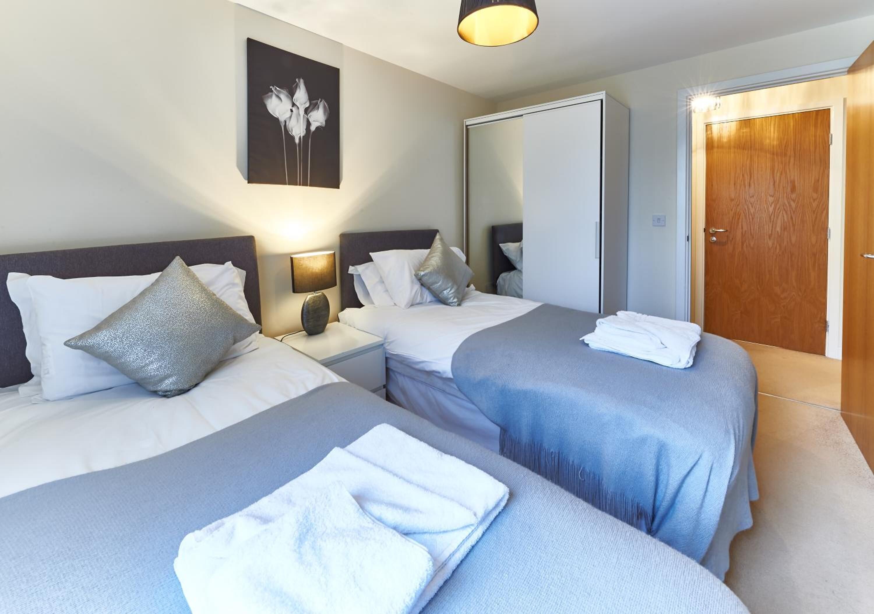 Camera d'albergo con due letti, un grande specchio, una porta in legno e un quadro appeso al muro.