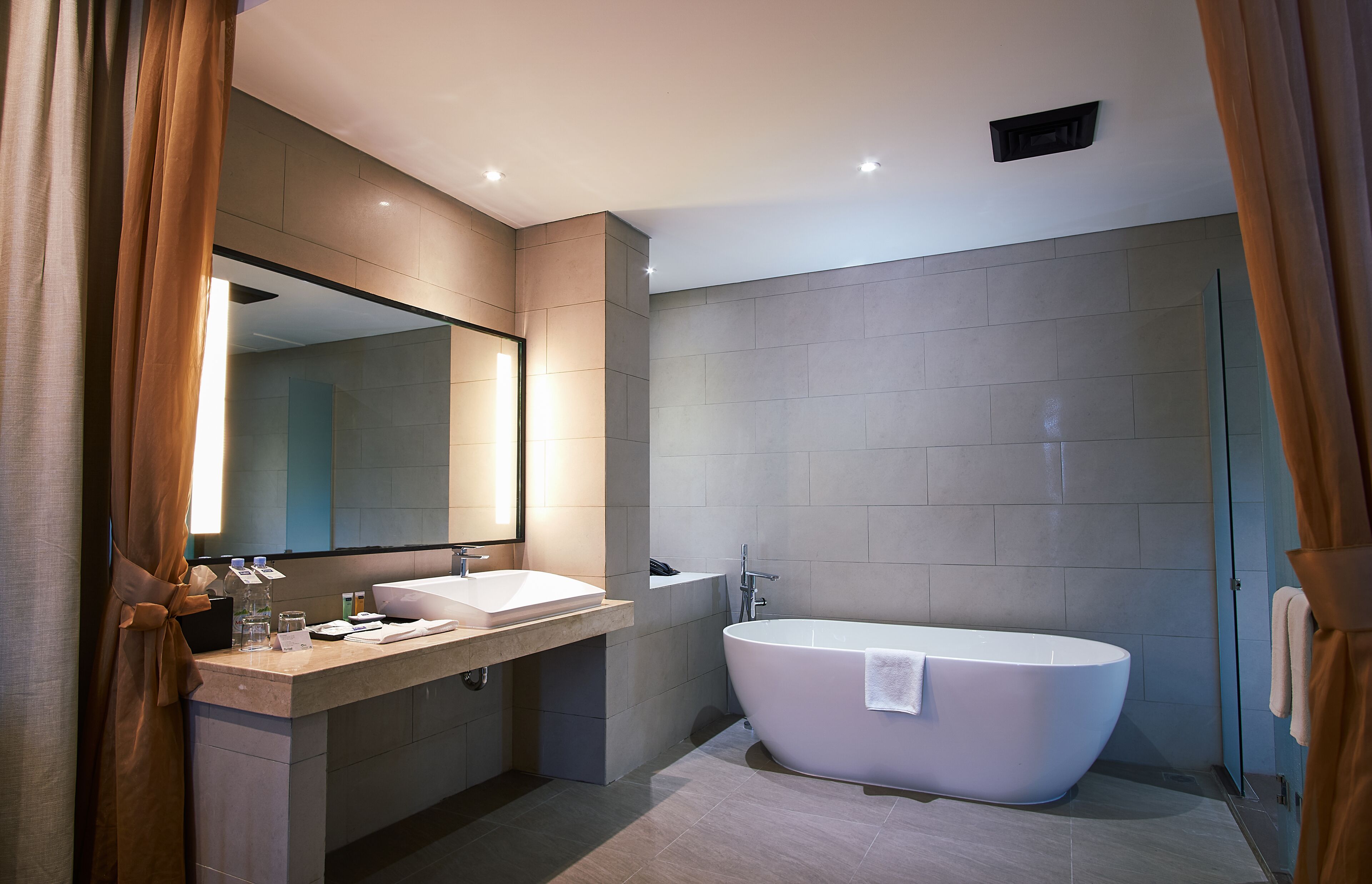 A modern bathroom with a freestanding bathtub, two sinks, a large mirror, and a shower area.