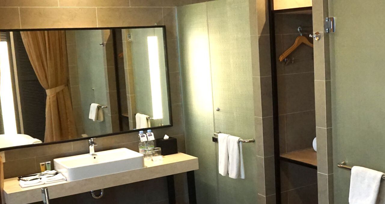 A modern bathroom with a large mirror, a sink, and a shower area.