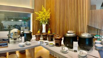 Disposição de buffet com vários recipientes de comida e uma planta decorativa.