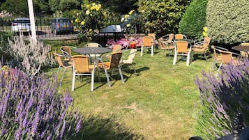 A garden patio with outdoor seating, surrounded by various plants and flowers.