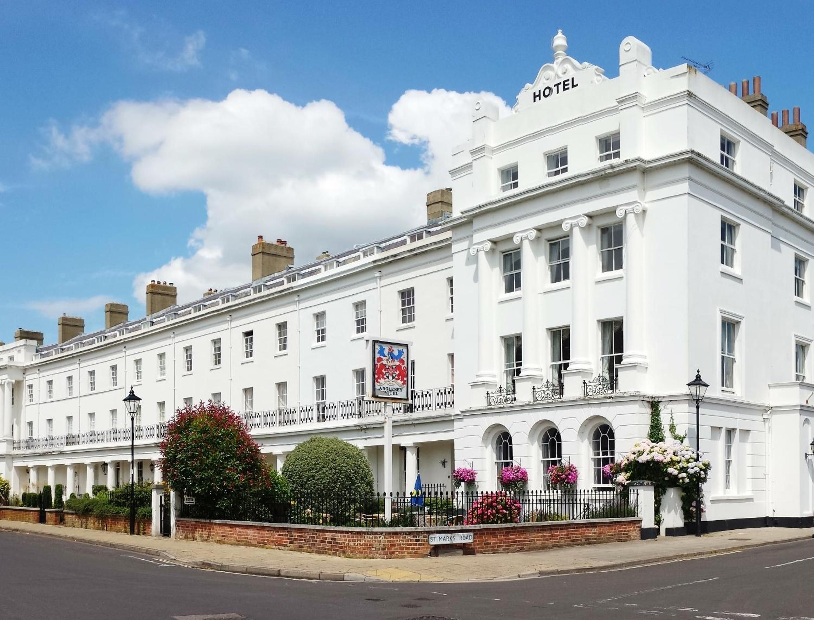 A white hotel with a classic architectural style, featuring a prominent 'HOTEL' sign at the top.