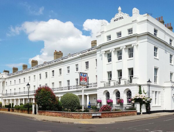A white hotel with a classic architectural style, featuring a prominent 'HOTEL' sign at the top.