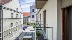Une rue étroite, bordée de bâtiments des deux côtés, une église avec un clocher et un ciel dégagé.