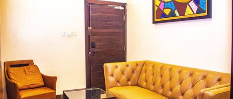 A living room with a brown leather sofa, a brown leather armchair, and a glass coffee table.
