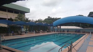 Une piscine à l’eau claire, entourée d’une terrasse carrelée, de chaises longues et de parasols.