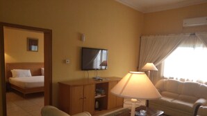 Une chambre d’hôtel avec un lit, un canapé, une table basse, une télévision et une lampe.