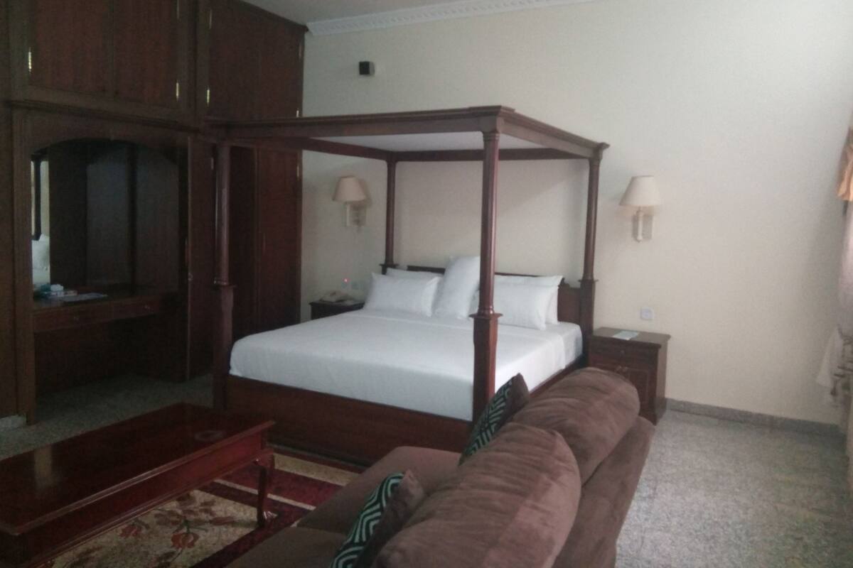 A four-poster bed with white linens, a wooden headboard, and two bedside lamps.