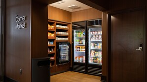 A corner market with wooden shelving, refrigerated display cases, and a trash bin. - Fairfield Inn & Suites by Marriott Atlanta Fairburn (Fairburn)