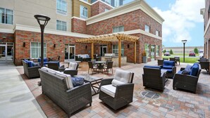 A patio area with wicker furniture and a barbecue setup. - Homewood Suites by Hilton Detroit (Warren)