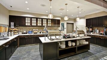 A modern kitchen with dark wood cabinets, a central island with a sink, and overhead pendant lighting.