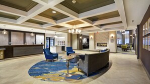 A spacious lobby with a reception desk, seating area, and a fireplace. - Homewood Suites by Hilton Detroit (Warren)