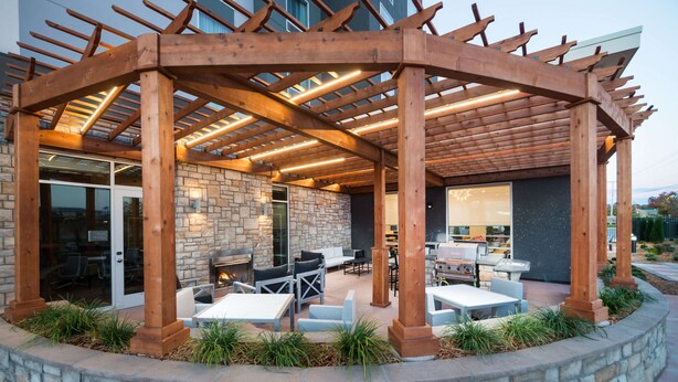 Eine Terrasse im Freien mit Holz-Pergola, Steinmauern und Gartenmöbeln.