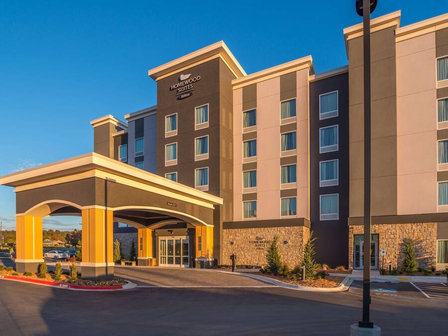 Un hotel moderno con una entrada central, varios pisos y fachada de piedra.