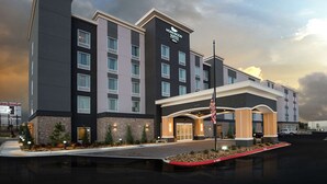 Ein modernes Hotel mit einer steinernen Fassade, mehreren Etagen und einer gut sichtbaren amerikanischen Flagge.