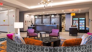 Eine Lobby mit einer Rezeption, Sitzgelegenheiten und einem Kühlschrank.