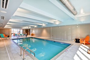 Una piscina interior con carriles definidos, zona de vestuarios y sillas anaranjadas.