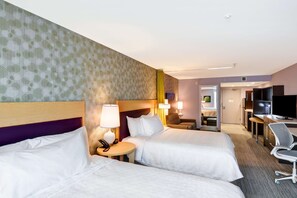 Una habitación de hotel con dos camas, un escritorio, una silla, un televisor y un baño.