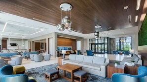 A spacious living area with a modern design, featuring a large sofa, multiple seating options, and a wooden coffee table.