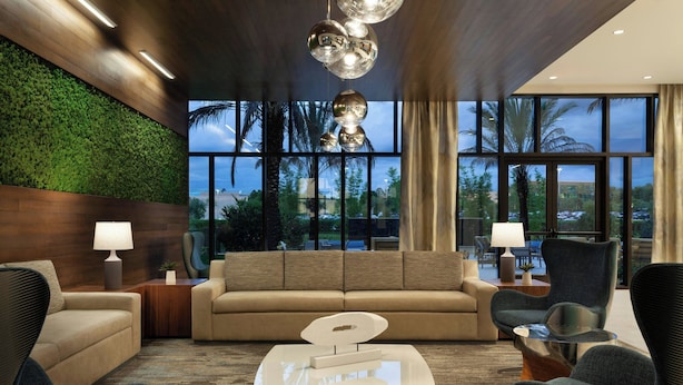 A modern living room with a sofa, two armchairs, a coffee table, and a green wall.